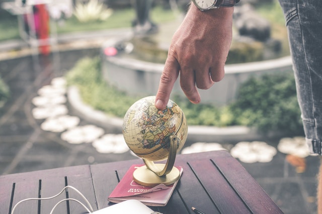 Hand pointing at mini globe