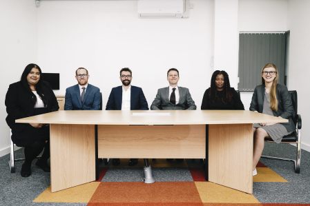 OTB Legals Personal Immigration Team sat in a line at a desk