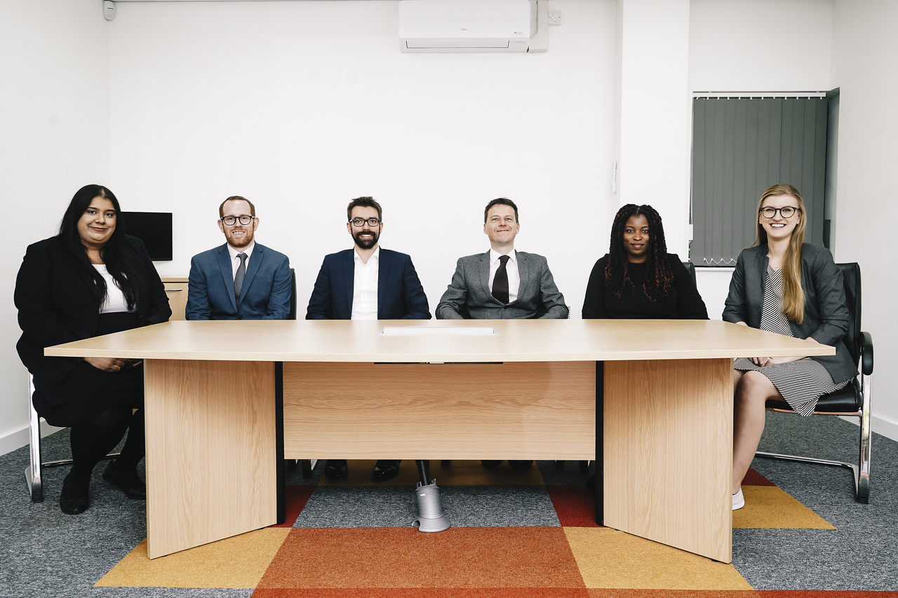 OTB Legals Personal Immigration Team sat in a line at a desk