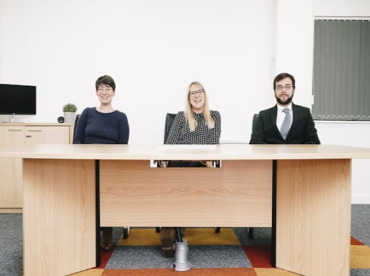 BIT Team OTB Legals Business Immigration Team sat at a desk smiling